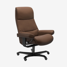 A brown upholstered office chair with a high back, padded armrests, and a black five-wheel base, shown on a plain light gray background.