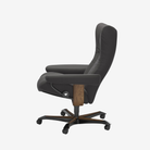 A dark gray upholstered office chair with a high back, wood-look center column detail, and a black five-star wheeled base, shown from a side profile on a light gray background.